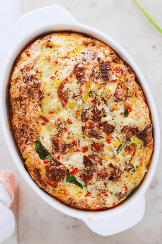 Overhead view of a golden-brown spinach and feta egg bake in a white casserole dish.