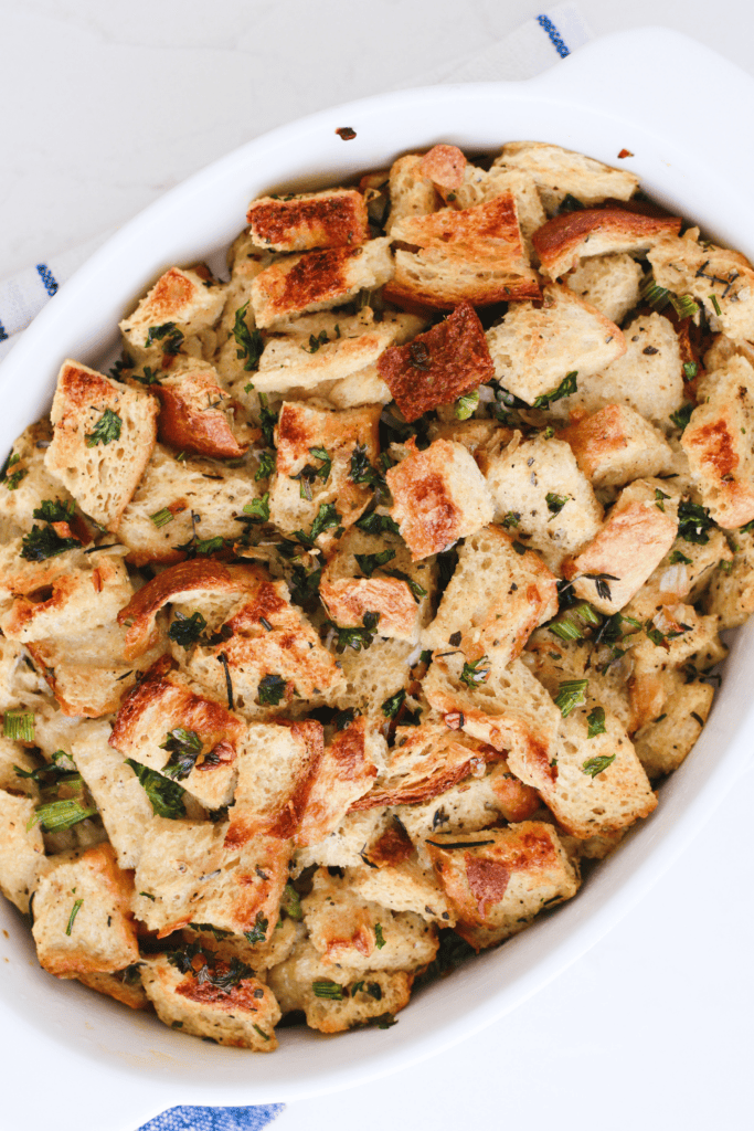 Top-down view of homemade keto stuffing with golden bread cubes and fresh green herbs, ready to serve.