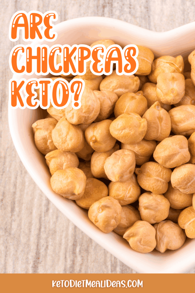 A heart-shaped bowl filled with chickpeas on a light wood surface.