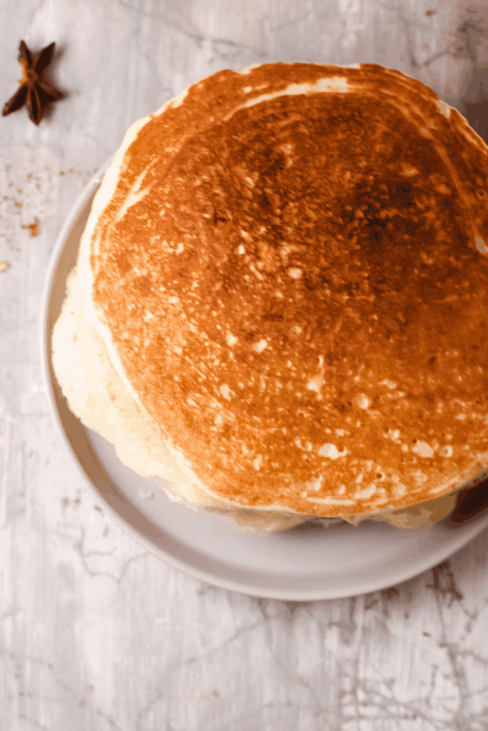 A top view of thick, golden keto pancakes stacked neatly on a plate.