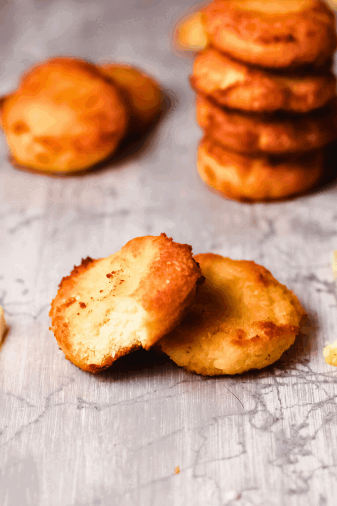 Close-up of keto citrus cheesecake cookies made with coconut flour and cream cheese, showing a golden low carb cookie broken open to reveal a soft, creamy cheesecake-style center.
