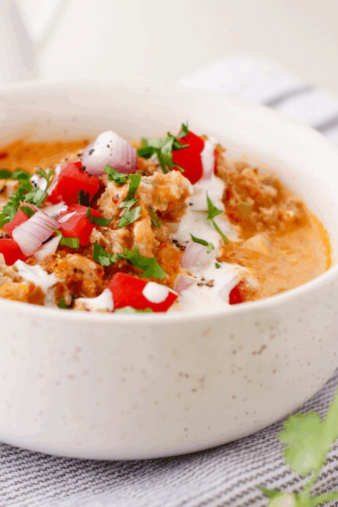 A creamy, low-carb beef soup garnished with herbs, showcasing its thick texture and savory flavor.